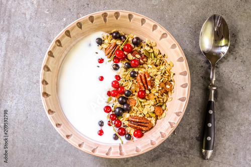 Bowl of homemade granola with yogurt and fresh berries on metallic background from top view