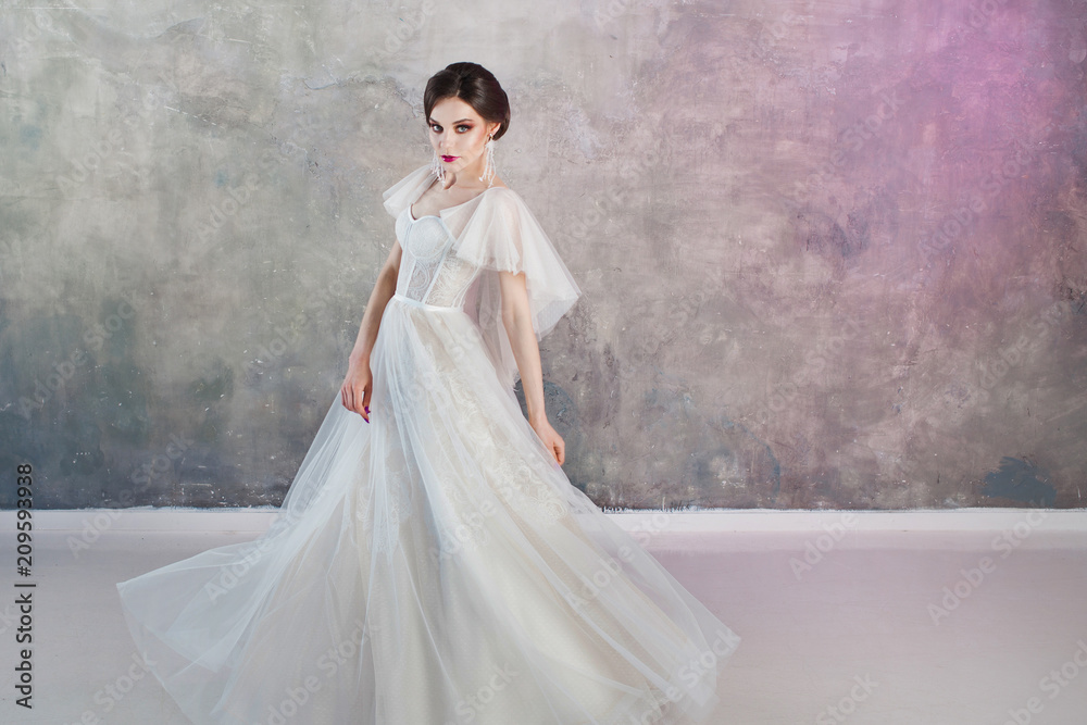 Beautiful and stylish bride in wedding dress in Studio on grey textured background Beautiful and stylish bride in wedding dress in Studio on grey textured background