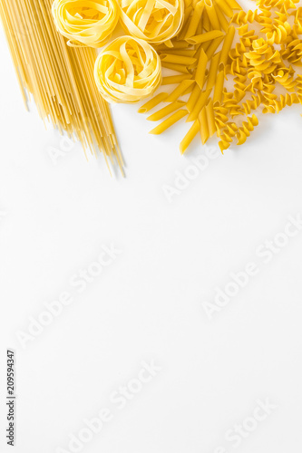 Types of pasta. Raw spaghetti, fusilli, penne, fettuccine on white background top view copy space