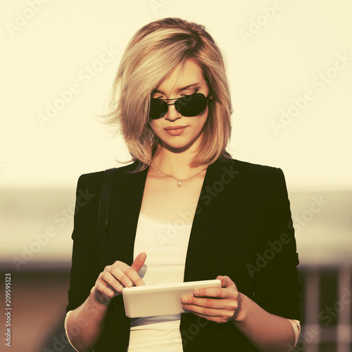 Stampa su tela Young fashion business woman in sunglasses using tablet computer in city street