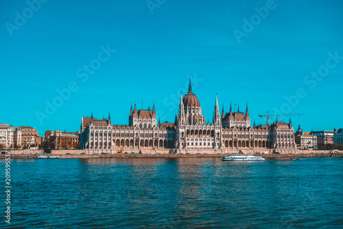 big parliament building of hungary with touristic ship in the foreground