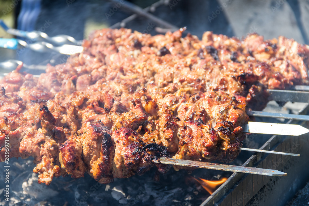 Grilled kebab cooking on metal skewer. Roasted meat cooked at barbecue Grilled kebab cooking on metal skewer. Roasted meat cooked at barbecue