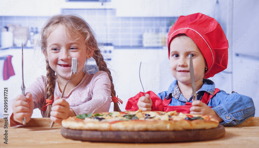 Two funny child girls friends with knives and forks want to eat pizza Two funny child girls friends with knives and forks want to eat pizza