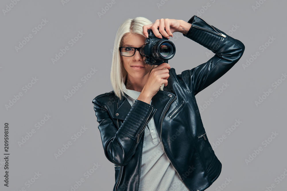 Beauty smart blonde female photographer in a white blouse and black leather jacket taking a photo at a studio. Beauty smart blonde female photographer in a white blouse and black leather jacket taking a photo at a studio.