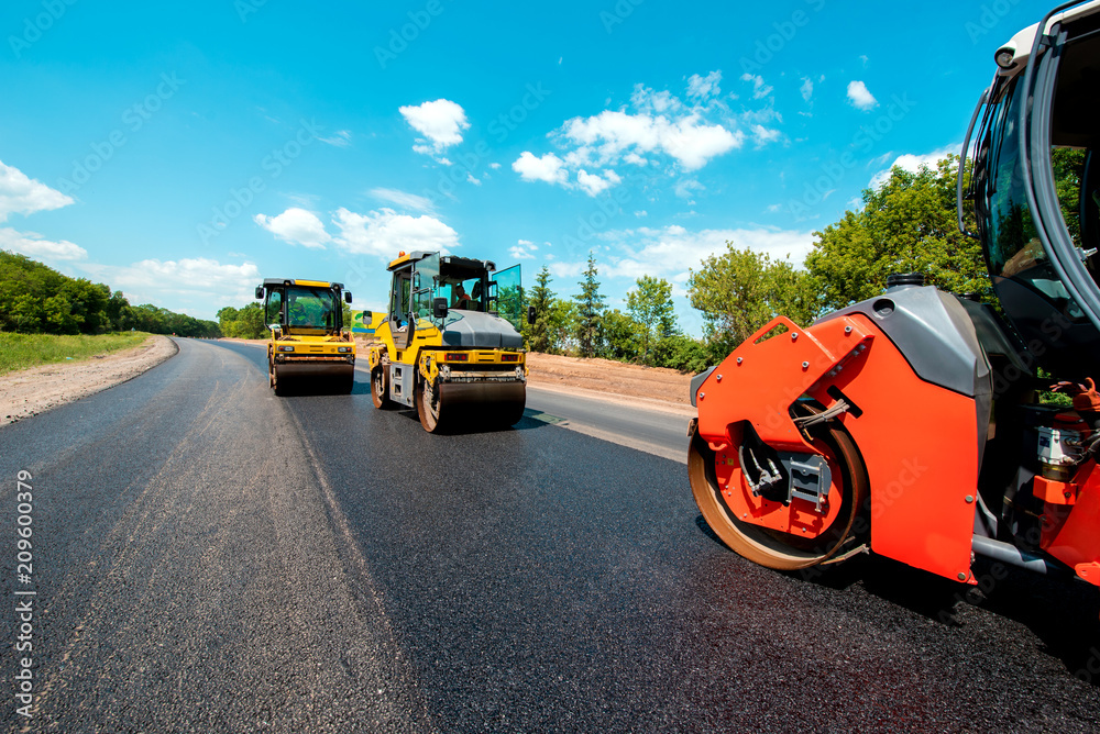 industrial landscape with rollers that rolls a new asphalt in the roadway. Repair, complicated transport movement.