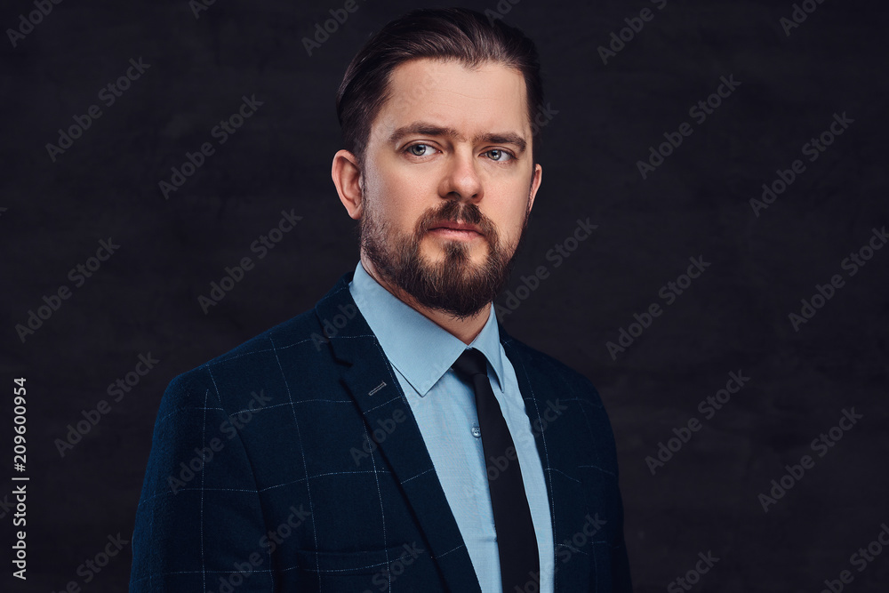 Close-up portrait of a handsome middle-aged man with beard and hairstyle dressed in an elegant formal suit. Isolated on a textured dark background in studio. Close-up portrait of a handsome middle-aged man with beard and hairstyle dressed in an elegant formal suit. Isolated on a textured dark background in studio.