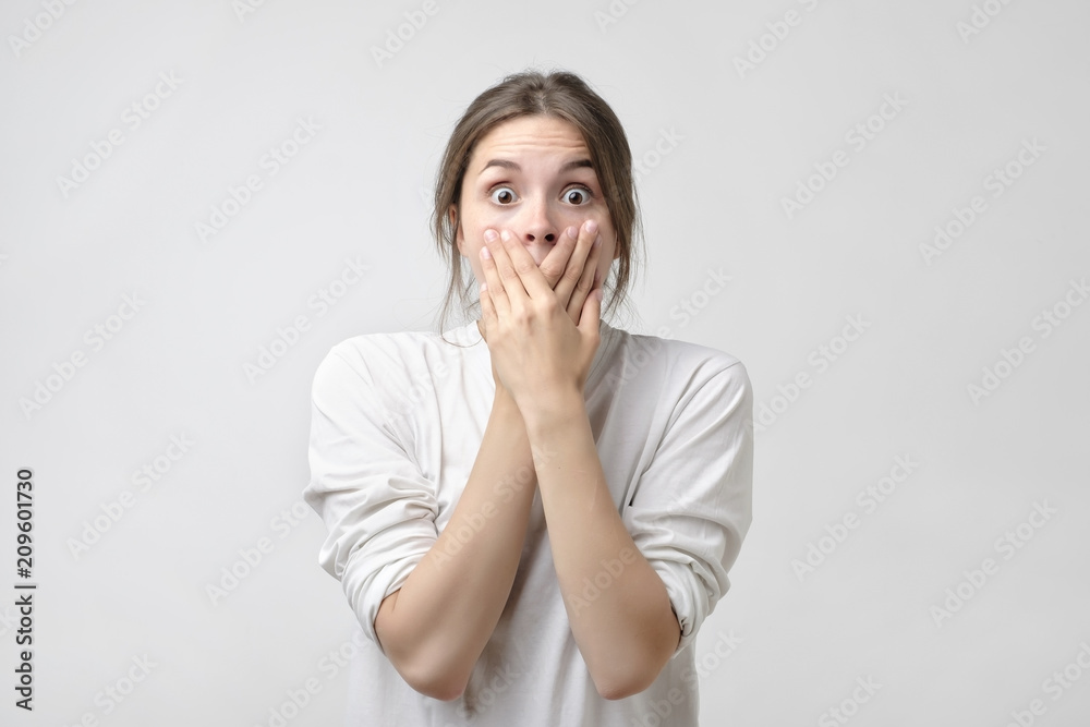 attractive, pretty,and charming, woman closed her mouth with crossed hands and wide opened eyes attractive, pretty,and charming, woman closed her mouth with crossed hands and wide opened eyes