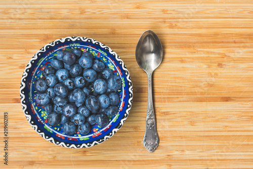 top view of blueberries in a colorful blue bowl on a wooden background