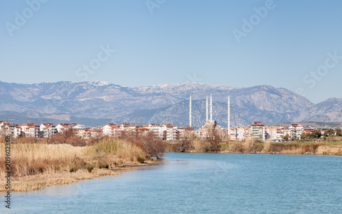 Fototapeta Naklejka Na Ścianę i Meble -  Manavgat River.  The view looking up Manavgat River towards the town of Manavgat in the province of Antalya, southern Turkey. Kulliye mosque, with its four minarets can be seen dominating the skyline.