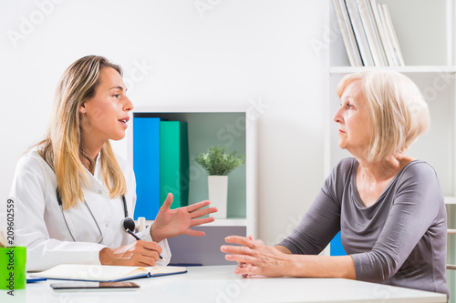 Female doctor and senior woman patient talking in doctor's office.