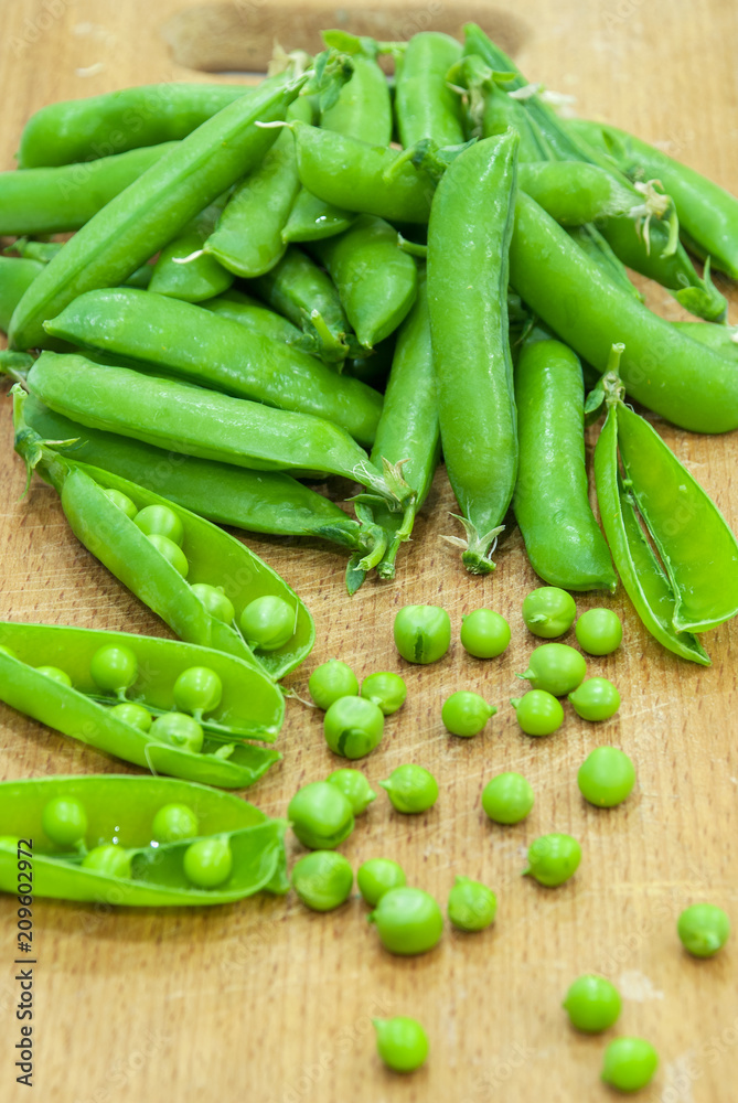 Fresh pods of sweet green peas in basket, on wooden board. Fresh pods of sweet green peas in basket, on wooden board.