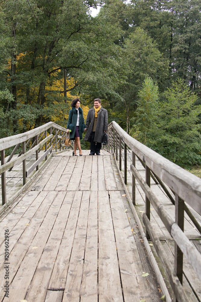  Mature couple walking on the wooden bridge. Casual wear. True love.