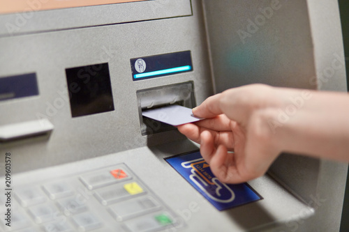 Someone takes off money from outdoor bank terminal, inserts plastic credit card in atm machine, going to withdraw money and get salary. Cash machine. Modern technologies and innovations concept