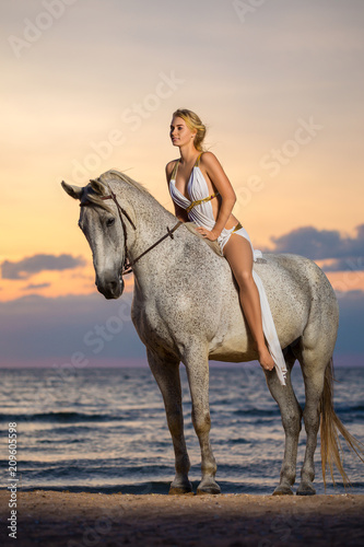 beautiful woman riding a horse on the sea background, entertainment concept