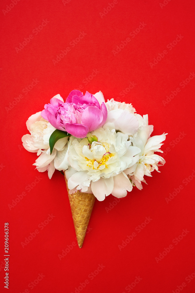 Waffle ice cream cone with white and pink peony flowers on red background. Summer concept. Copy space, top view.