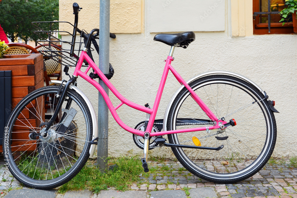 Pink bicycle Bikes available for rental, parked in the city center.