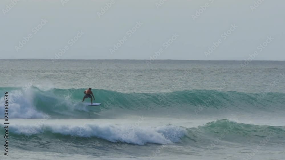 Surfer rides a long wave slow motion at beach in Bali Indonesia Surfer rides a long wave slow motion at beach in Bali Indonesia