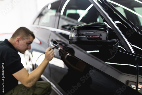 Car detailing - Worker with orbital polisher in auto repair shop. Selective focus.