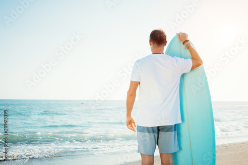 Photography Portrait of happy surfer in hawaiian t-shirt walking with surf board on the beac