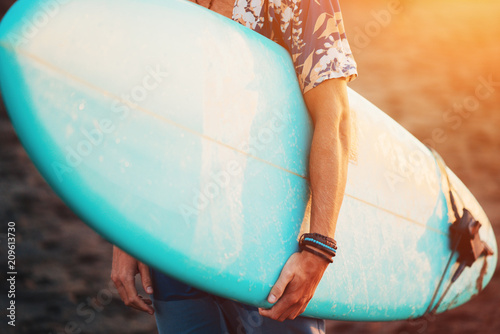 Photography Portrait of happy surfer in hawaiian t-shirt walking with surf board on the beac