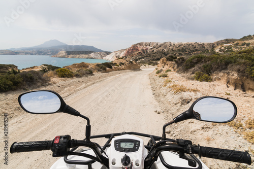 ATV quad bike parked on the coastal road along Aegean sea on Milos island, Greece
