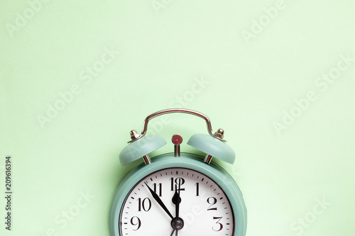 Retro style alarm clock over the pastel mint green background