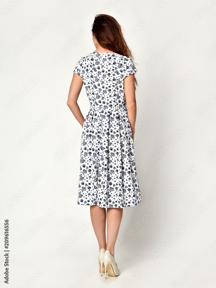 Young beautiful woman posing in new blue flowers casual summer dress on grey Young beautiful woman posing in new blue flowers casual summer dress on grey