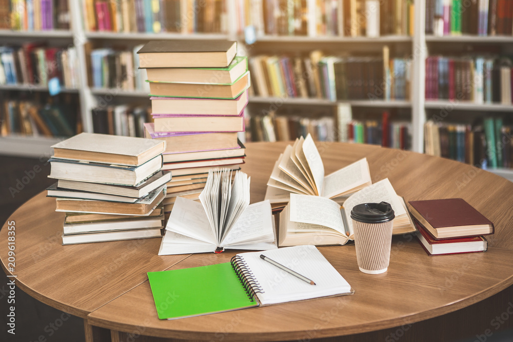 Fototapeta premium Close up volumes, opened copybook and cup of coffee locating on desk in athenaeum