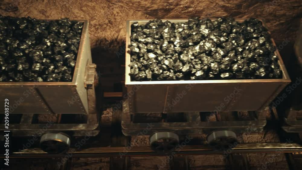 Top of a coal mine wagons slowly moving through narrow underground tunnel. Top of a coal mine wagons slowly moving through narrow underground tunnel.