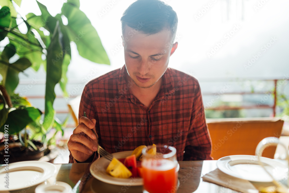 guy eats breakfast from fruit on a sunny terrace guy eats breakfast from fruit on a sunny terrace