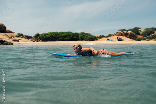   girl floats on a surf catches a wave. Against the shore © Аrtranq