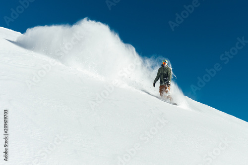 snowboarder in gear brakes on slope freeride brakes creating a wave of snow