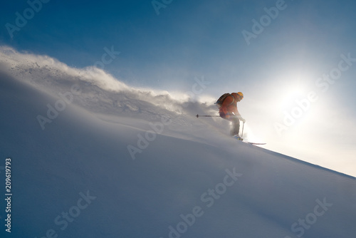 skier rides freeride on powder of snow leaving wave