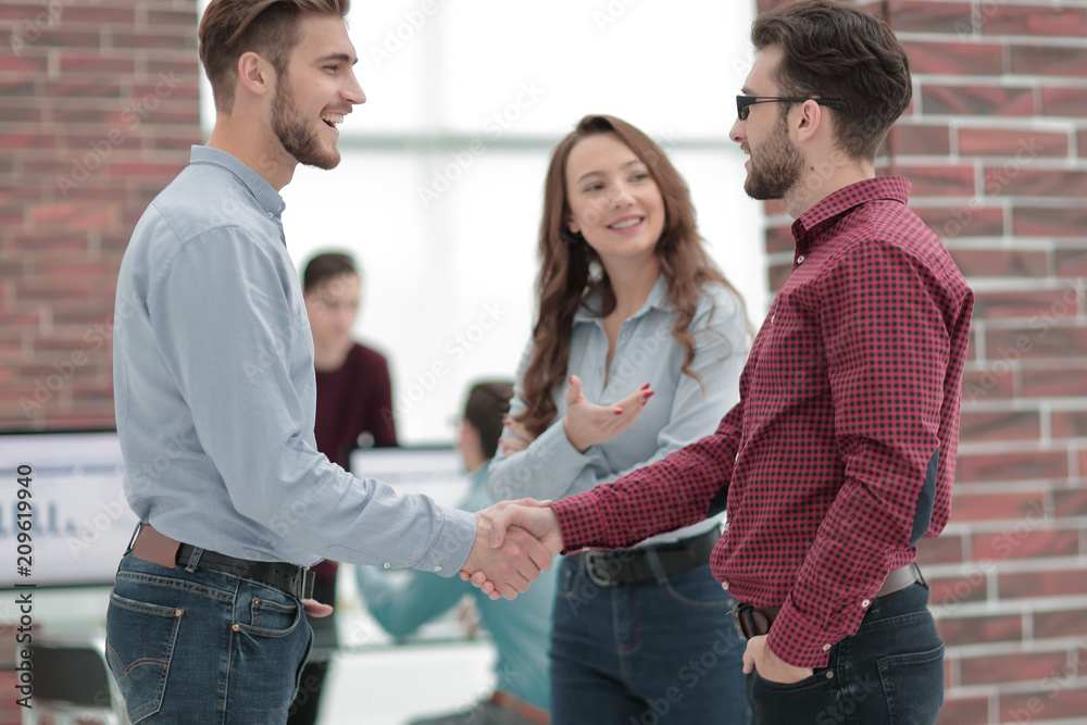 Smiling businessman shaking hands with colleague in office. Smiling businessman shaking hands with colleague in office.