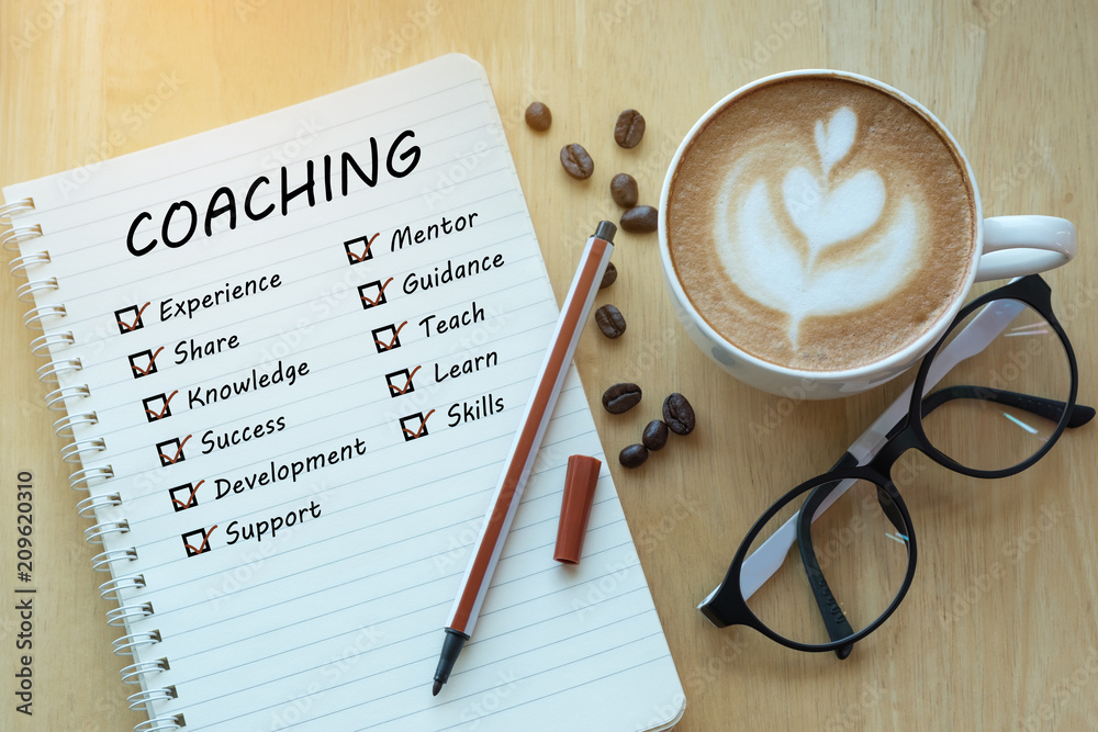 coaching and check list marks in notebook with glasses, pencil and coffee cup on wooden table. Project management concept. - obrazy, fototapety, plakaty 