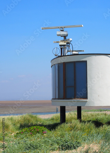 the old coastguard station in fleetwood with radar antennae with crass covered dunes leading to the beach on a summers day in bright sunlight with blue sky