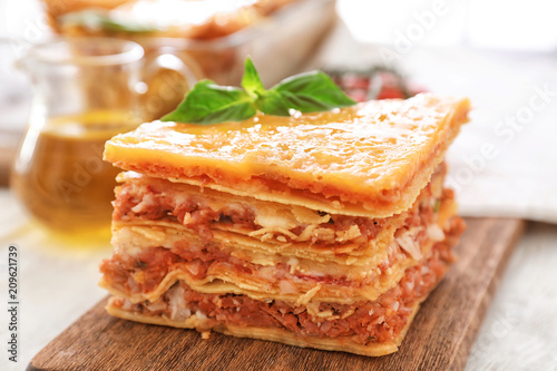 Portion of tasty lasagna on wooden board