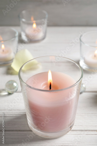 Beautiful burning wax candle in glass on table