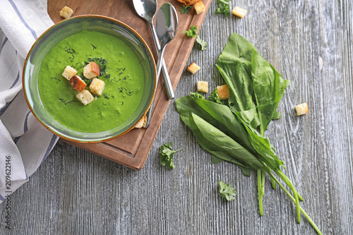 Bowl with delicious spinach soup on wooden board