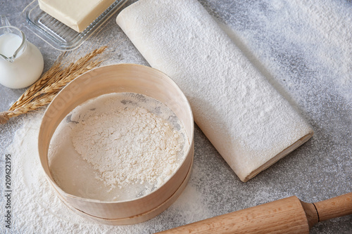 Raw flaky dough with flour on table