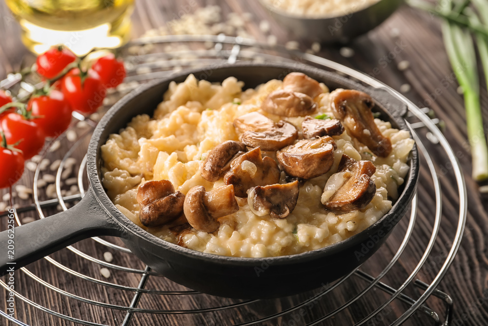 Frying pan with risotto and mushrooms on wooden table Frying pan with risotto and mushrooms on wooden table