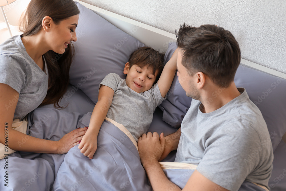 Parents with little son in bed. Family bedtime