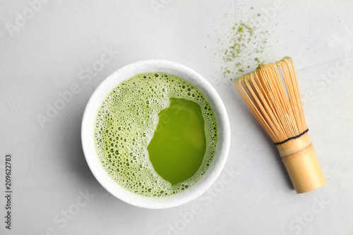 Chawan with fresh matcha tea and chasen on grey background, top view