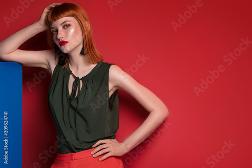 Fashionable redhead woman posing in studio.