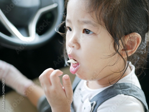 Fototapeta Little Asian baby girl, 24 months old, is choking while eating a piece of apple