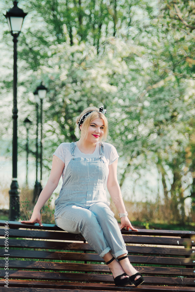 A girl is sitting on a bench with a sprig of cherry blossoms in her hands. A girl is sitting on a bench with a sprig of cherry blossoms in her hands.
