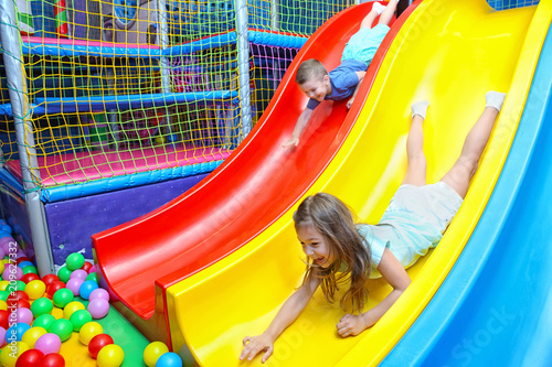 Принти на полотні Cute children riding on slide in entertainment center