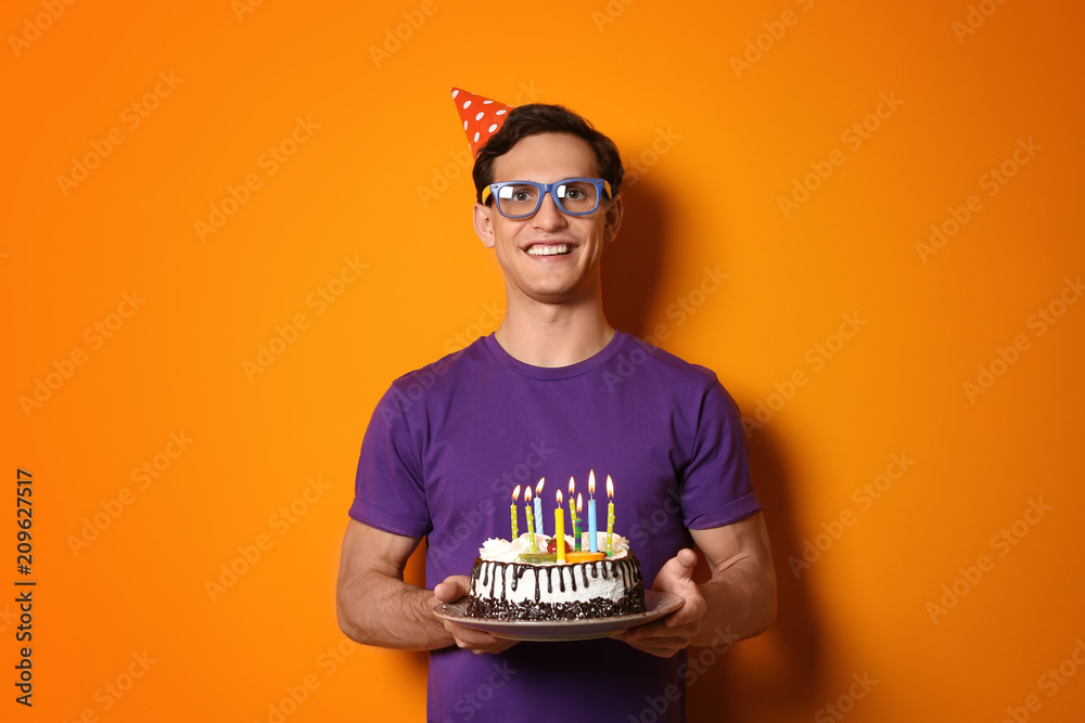 Young man with birthday cake on color background Young man with birthday cake on color background