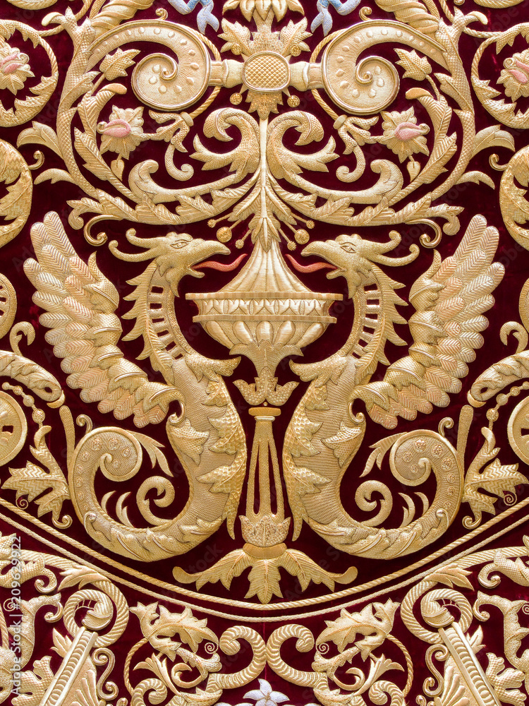 Detail of two dragons embroidered in gold on red velvet in the mantle of the Virgin of Regla, Holy Week in Seville, Spain