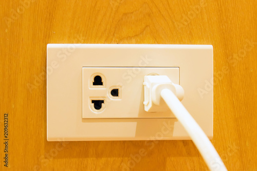 Two sockets with one plug on a wooden wall